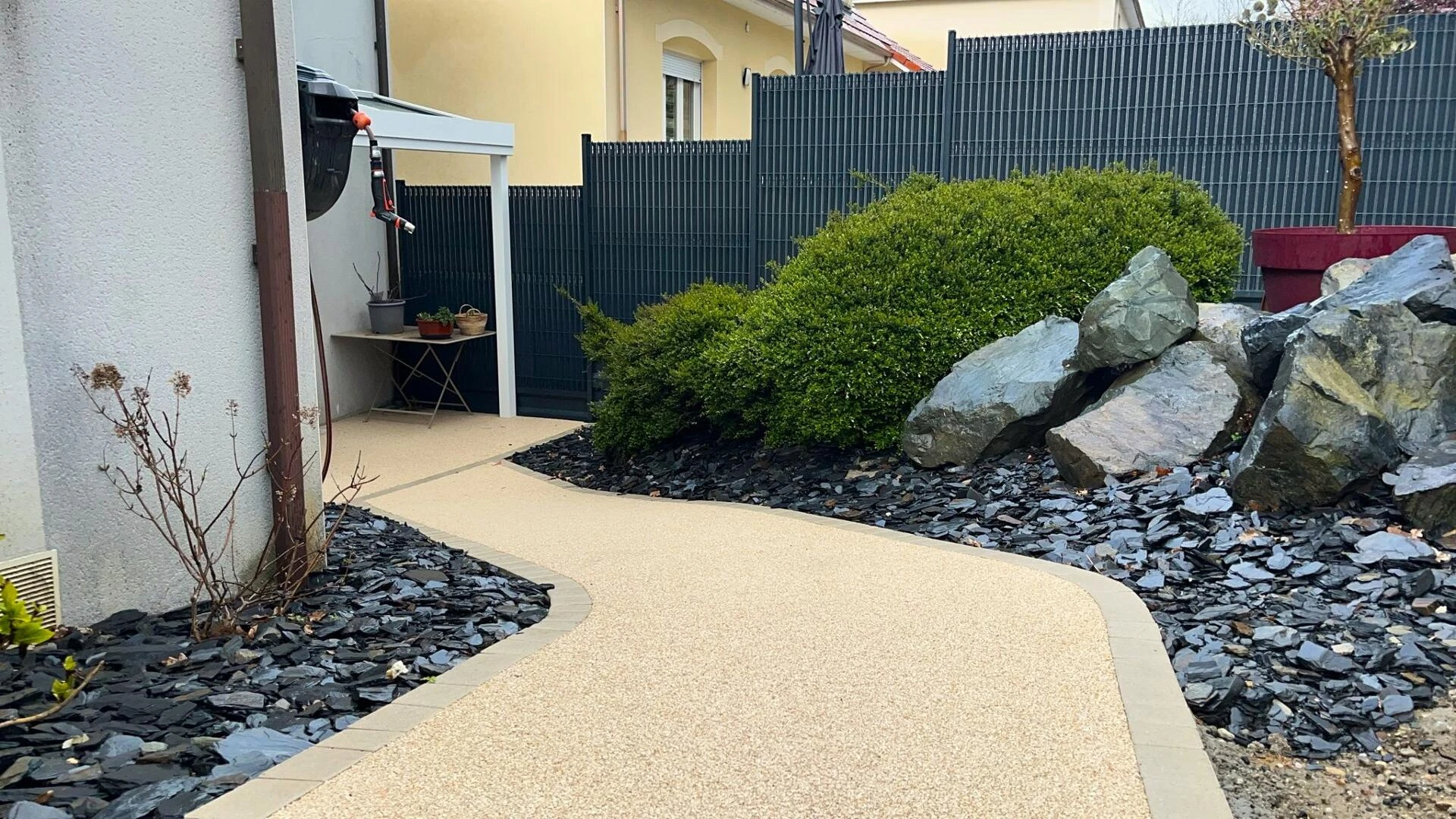 Allée piétonne en Hydrostar et bordures en pavés +création paysagère en ardoise noire et roche