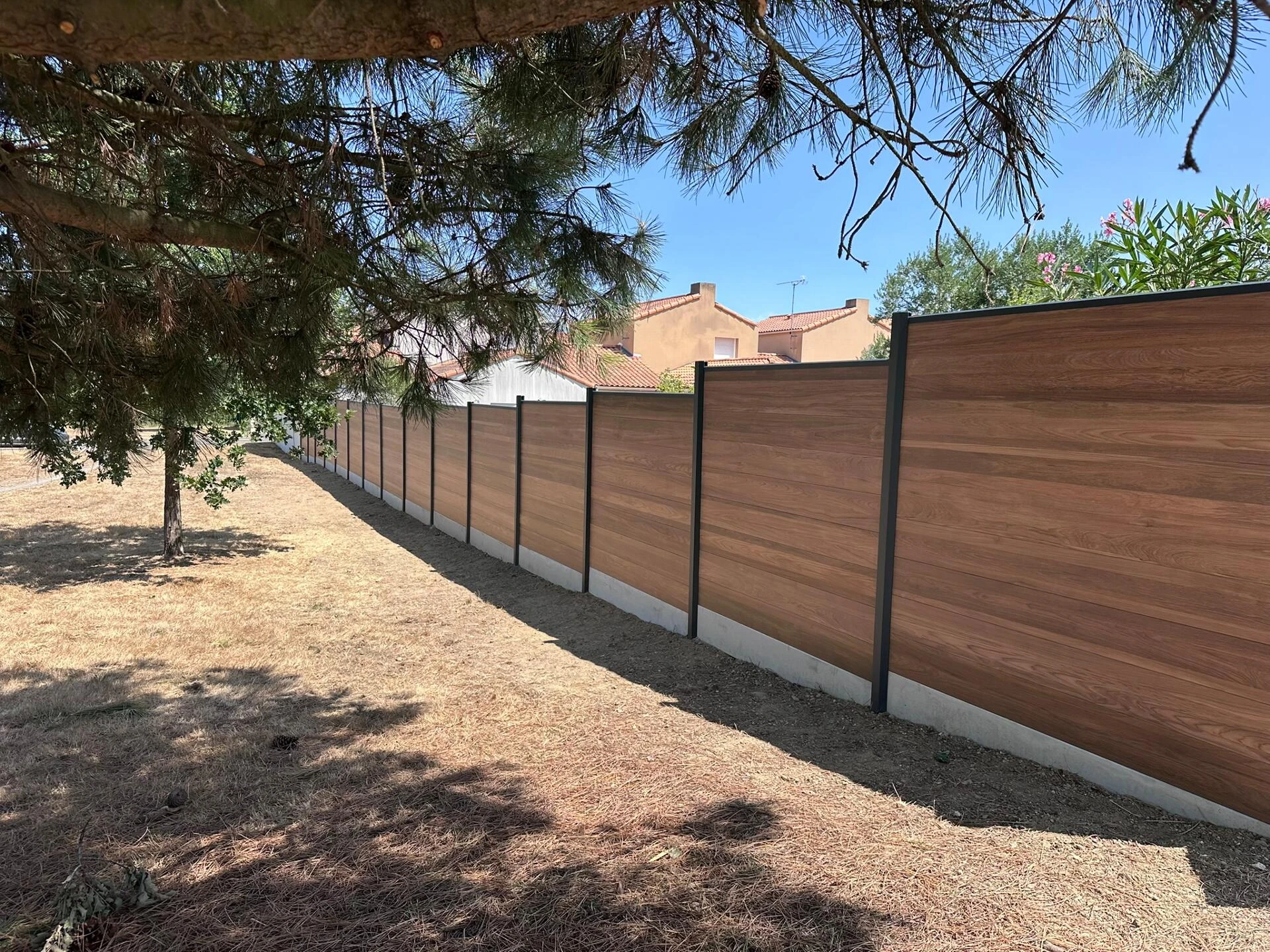 Clôture DoMaStyl' plein Effet bois Teck et poteaux gris 7016 avec plaques de soubassement béton